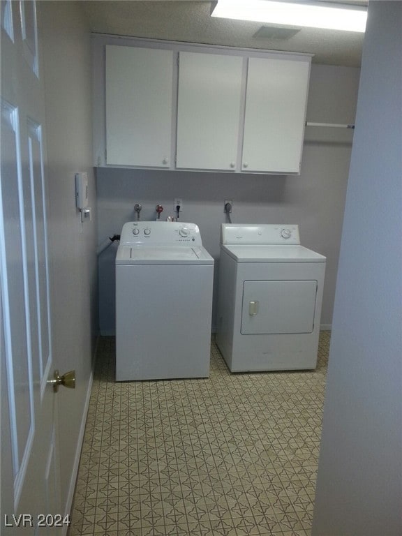 clothes washing area with cabinets and washing machine and clothes dryer