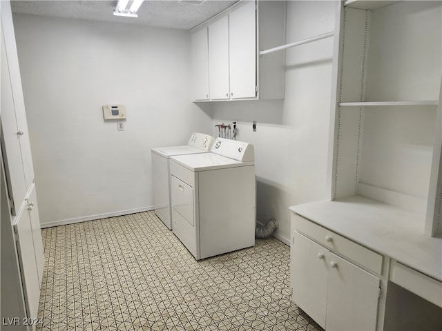 washroom featuring washer and dryer, cabinets, and a textured ceiling