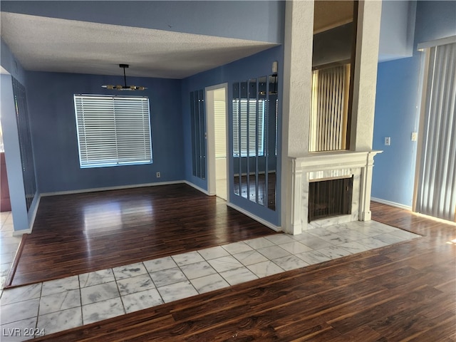 unfurnished living room with hardwood / wood-style floors, a textured ceiling, and an inviting chandelier