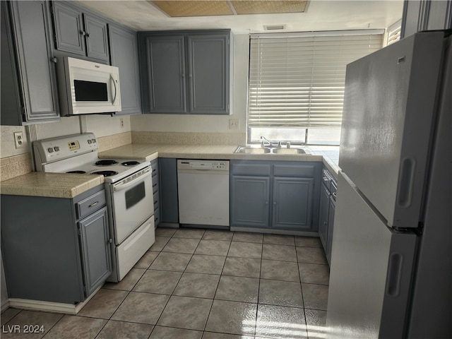 kitchen with light tile patterned flooring, white appliances, gray cabinets, and sink