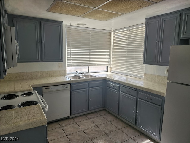 kitchen with gray cabinets, white appliances, sink, and light tile patterned floors