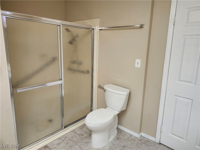 bathroom featuring tile patterned flooring, a shower with door, and toilet