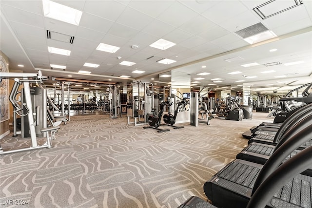 gym with light carpet and a paneled ceiling