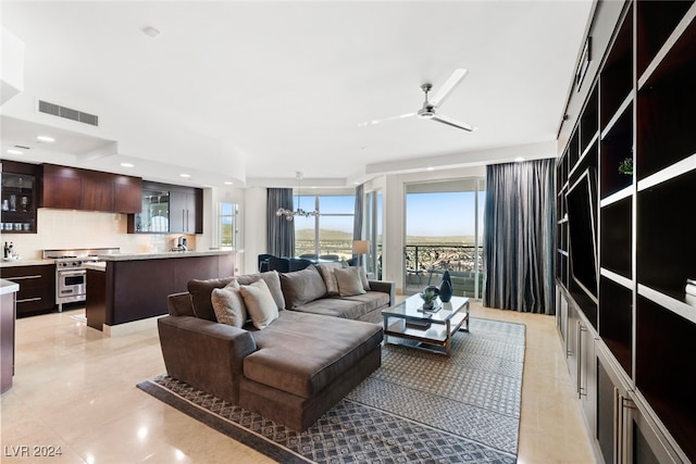 tiled living room with ceiling fan with notable chandelier