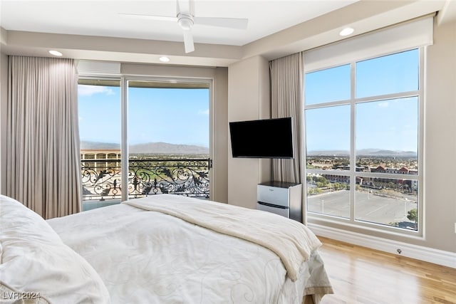 bedroom featuring ceiling fan, access to exterior, multiple windows, and hardwood / wood-style floors