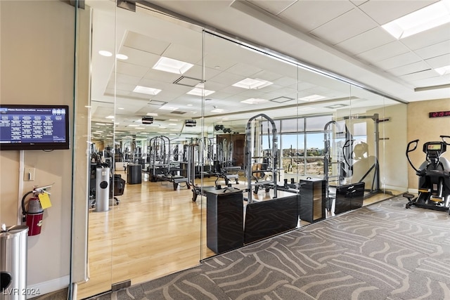 workout area featuring a drop ceiling and wood-type flooring