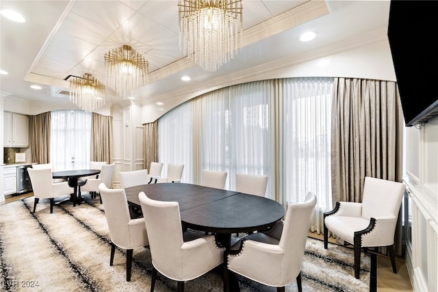 dining space featuring a notable chandelier, ornamental molding, a tray ceiling, and light wood-type flooring