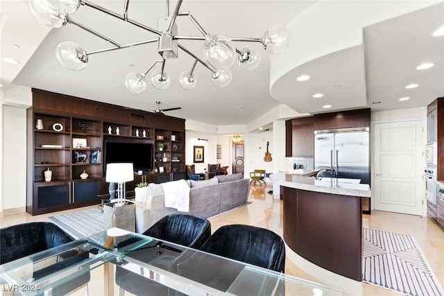 kitchen with dark brown cabinetry, built in appliances, and ceiling fan