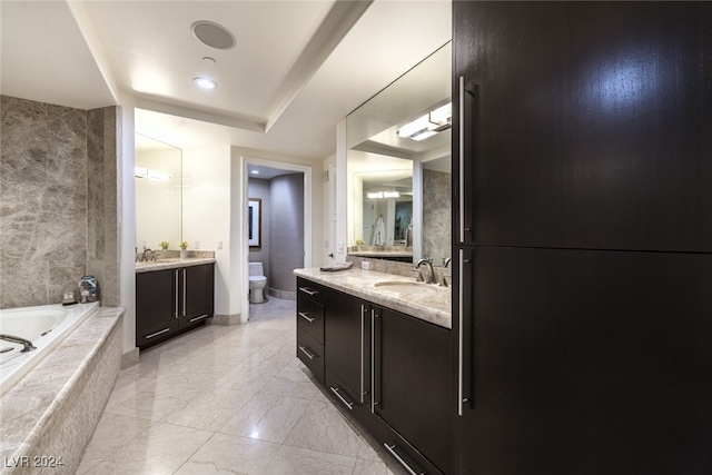 bathroom featuring vanity, tiled tub, and toilet