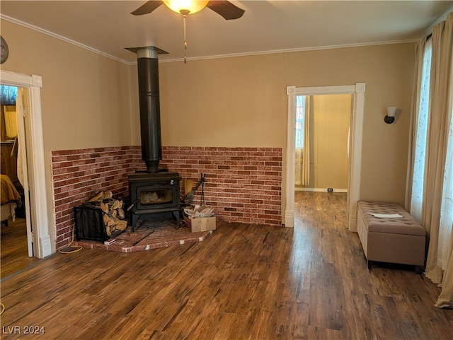 living room featuring crown molding, hardwood / wood-style flooring, a wood stove, and ceiling fan