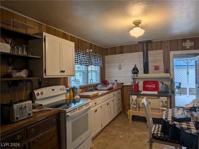 kitchen with wood walls, white electric range oven, and white cabinets