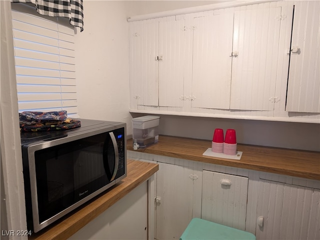 kitchen with butcher block counters and white cabinetry