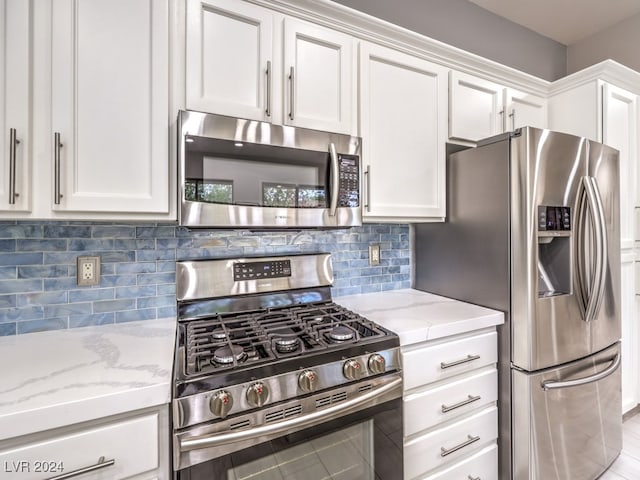 kitchen with white cabinets, stainless steel appliances, light stone counters, and decorative backsplash