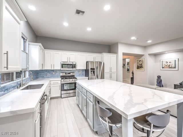 kitchen featuring sink, white cabinets, appliances with stainless steel finishes, and a kitchen bar