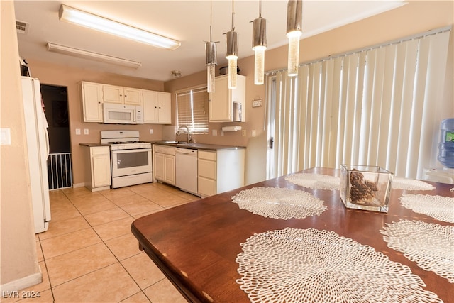 kitchen featuring white appliances, sink, hanging light fixtures, white cabinetry, and light tile patterned floors