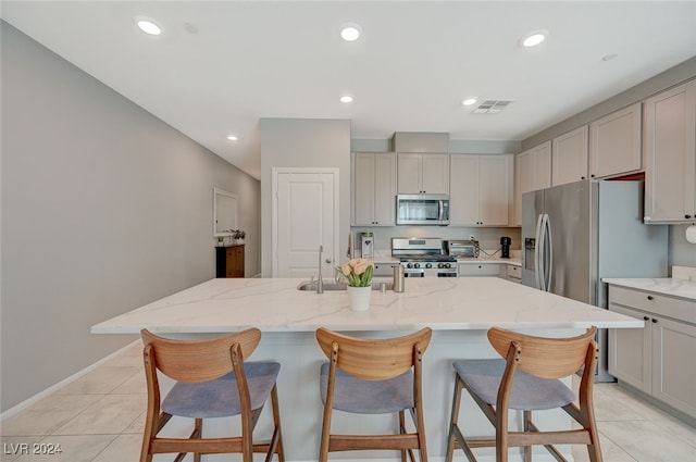 kitchen featuring appliances with stainless steel finishes, a center island with sink, and light tile patterned floors