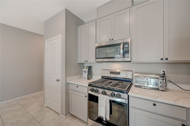 kitchen with white cabinets, light stone counters, stainless steel appliances, and light tile patterned floors