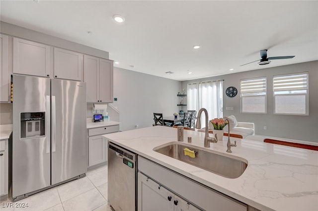 kitchen featuring light stone countertops, sink, appliances with stainless steel finishes, and light tile patterned flooring