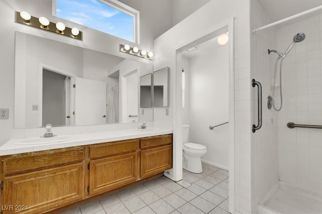 bathroom featuring toilet, vanity, tile patterned floors, and tiled shower