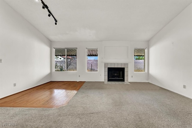 unfurnished living room with light hardwood / wood-style floors, track lighting, and a fireplace