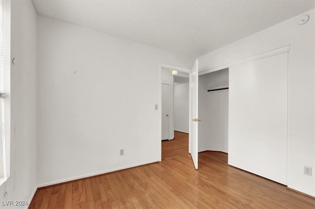 unfurnished bedroom with a closet, hardwood / wood-style flooring, and a textured ceiling