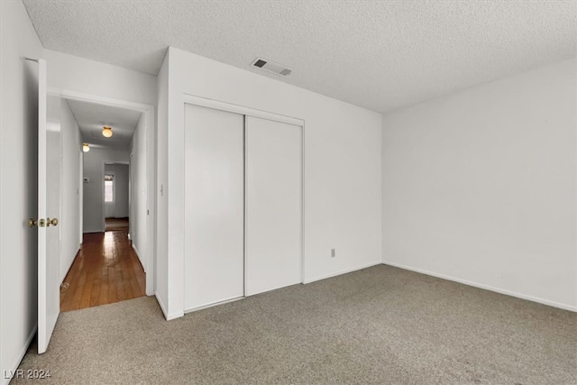 unfurnished bedroom with a closet, a textured ceiling, and wood-type flooring