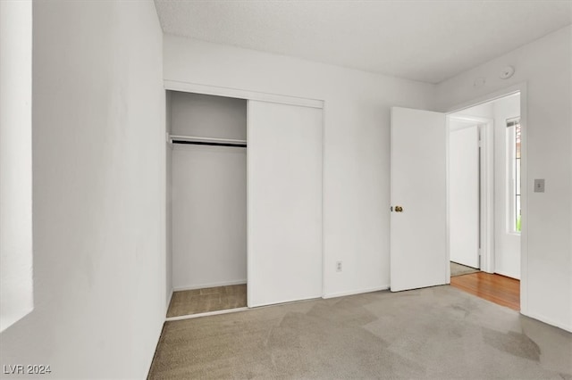 unfurnished bedroom featuring a closet and light colored carpet