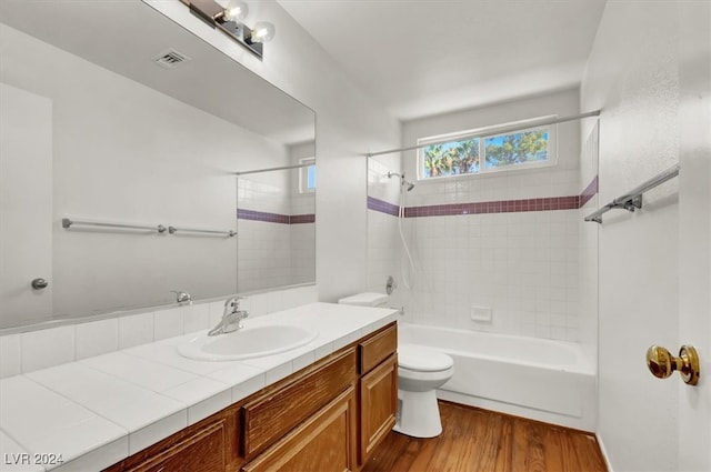 full bathroom featuring toilet, tiled shower / bath, vanity, and wood-type flooring