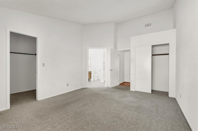 unfurnished bedroom with connected bathroom and carpet floors