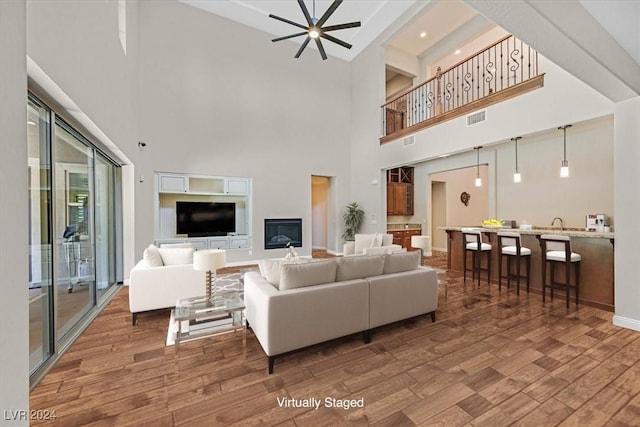 living room featuring hardwood / wood-style floors, ceiling fan, and a high ceiling