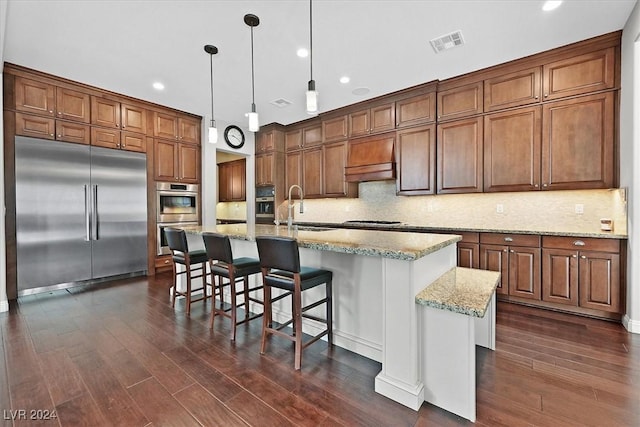 kitchen featuring sink, an island with sink, appliances with stainless steel finishes, and dark wood-type flooring