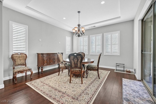 dining room with a tray ceiling, dark hardwood / wood-style flooring, and an inviting chandelier