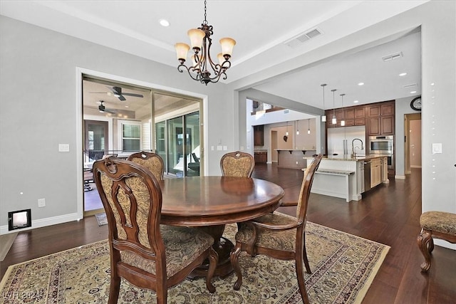 dining space featuring ceiling fan with notable chandelier, dark hardwood / wood-style floors, and sink