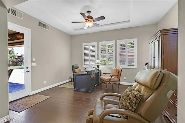 living area with ceiling fan, plenty of natural light, and dark wood-type flooring