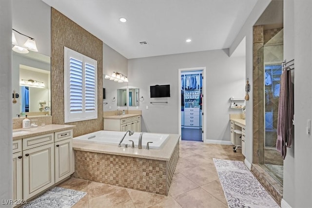 bathroom with tile patterned flooring, vanity, and tiled tub