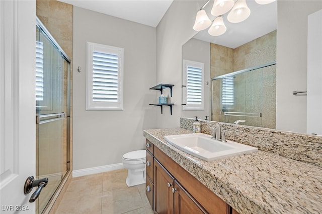 bathroom featuring tile patterned flooring, vanity, toilet, and an enclosed shower