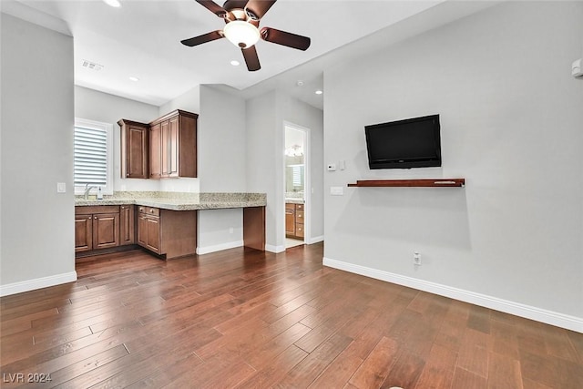 kitchen featuring dark hardwood / wood-style floors, ceiling fan, light stone counters, and sink