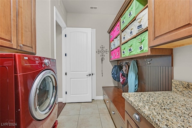 clothes washing area with cabinets, washer / dryer, and light tile patterned flooring