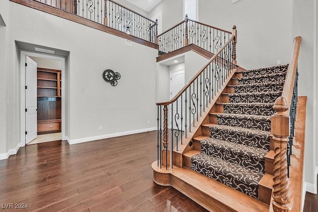 stairs with hardwood / wood-style flooring and a towering ceiling