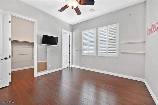 unfurnished bedroom featuring dark hardwood / wood-style flooring, a closet, a spacious closet, and ceiling fan