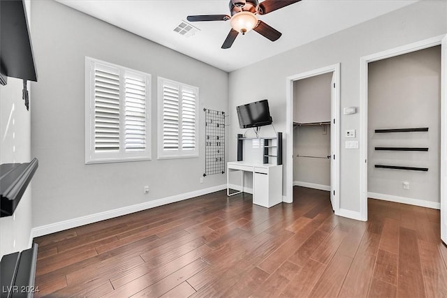 bedroom with a walk in closet, ceiling fan, a closet, and dark wood-type flooring