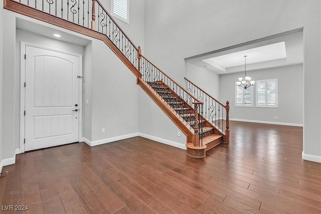 entryway with a notable chandelier, a raised ceiling, and dark wood-type flooring