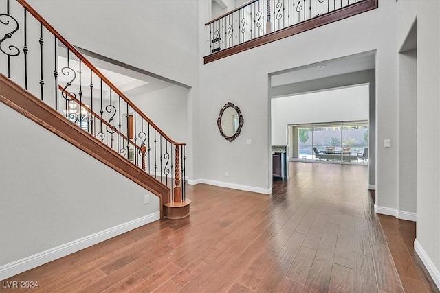 foyer featuring a towering ceiling and wood-type flooring