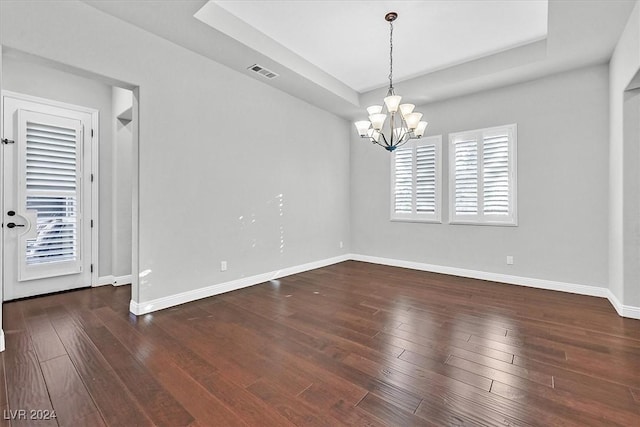 spare room with dark hardwood / wood-style floors, a wealth of natural light, and an inviting chandelier