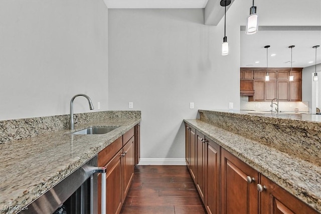 kitchen with light stone countertops, dark hardwood / wood-style floors, hanging light fixtures, and sink