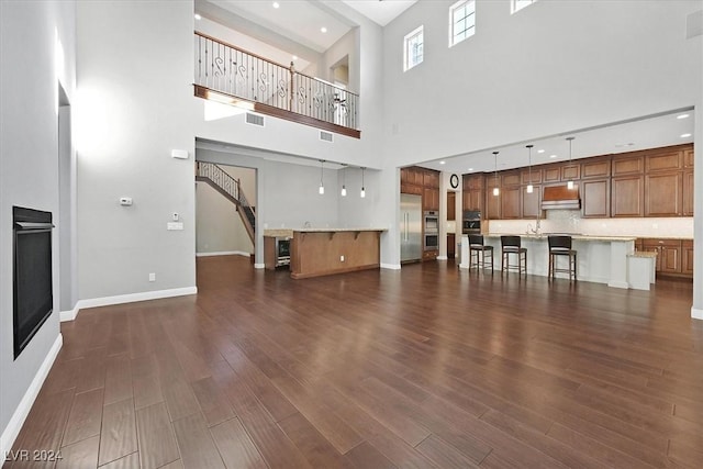 unfurnished living room with a towering ceiling and dark hardwood / wood-style floors