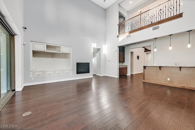 unfurnished living room featuring dark hardwood / wood-style flooring and a high ceiling