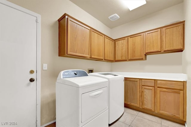 laundry room with washer and dryer, light tile patterned floors, and cabinets