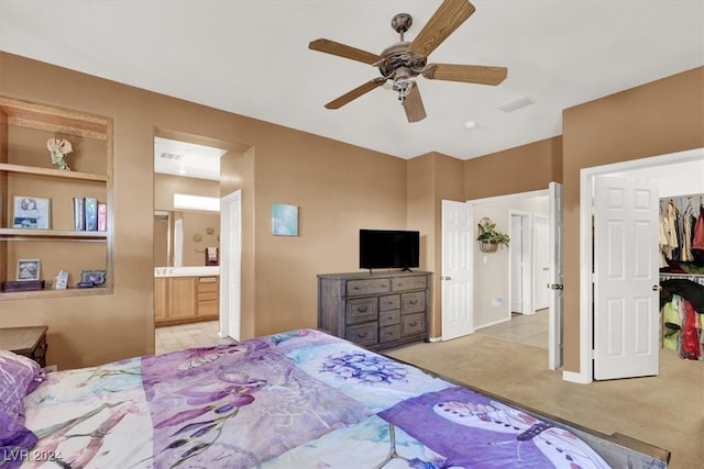 carpeted bedroom featuring a walk in closet, ensuite bathroom, a closet, and ceiling fan