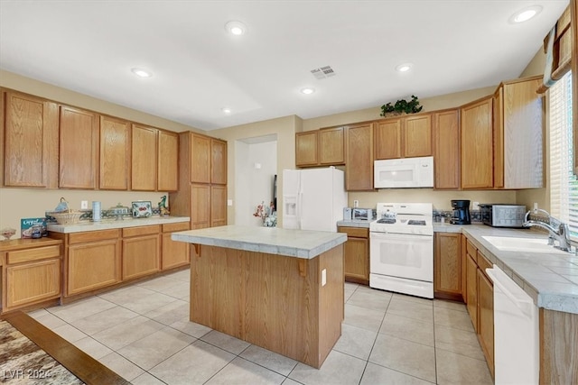 kitchen featuring light tile patterned floors, sink, a kitchen island, and white appliances